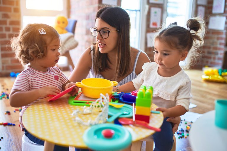 Young Beautiful Teacher And Toddlers Playing Meals Using Plastic