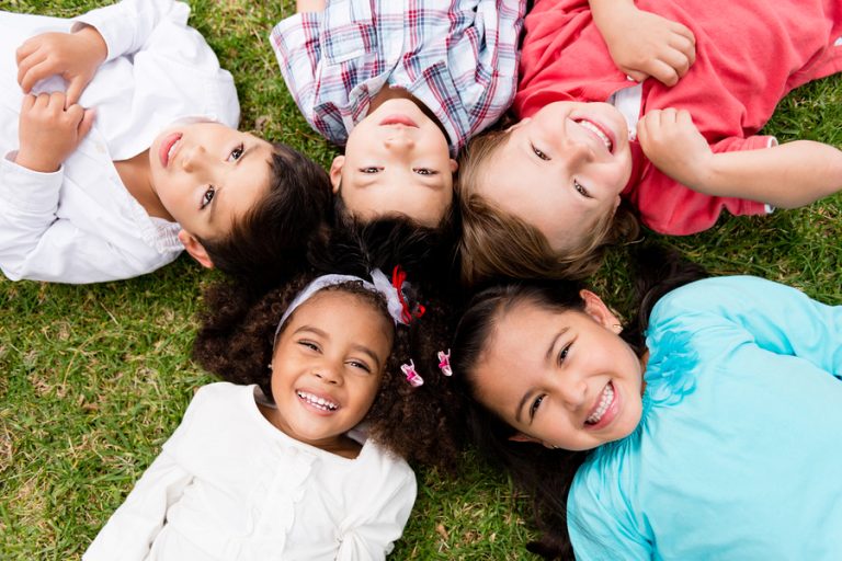 happy group of kids lying on the floor in a circle